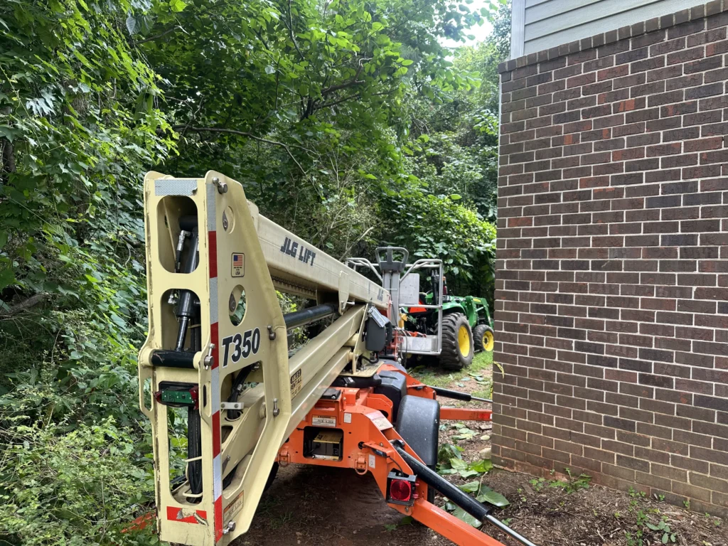 Tree service lift and equipment positioned beside a home during storm damage cleanup